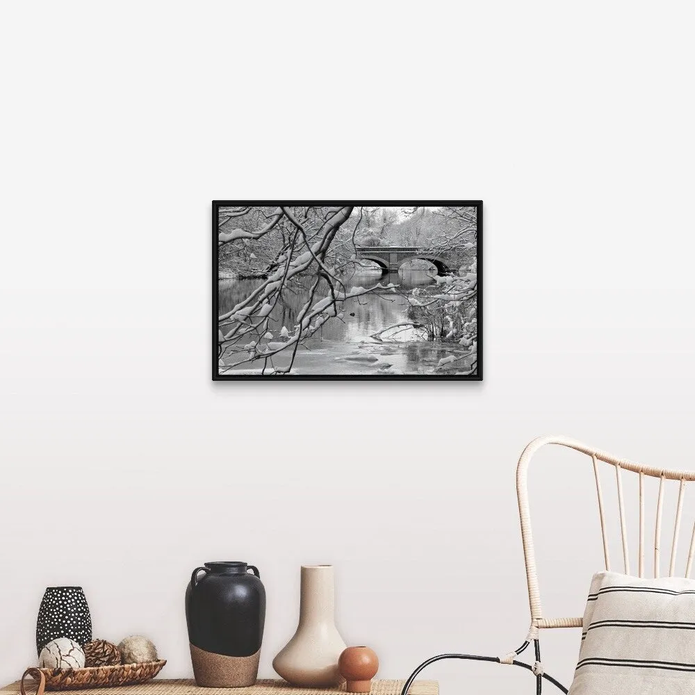 "Arch bridge over partially frozen river seen trough snow covered branches." Black Float Frame Canvas Art